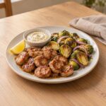 Air fryer maple Dijon chicken sausage slices with crispy Brussels sprouts, red onion and mustard yogurt dip on a white plate